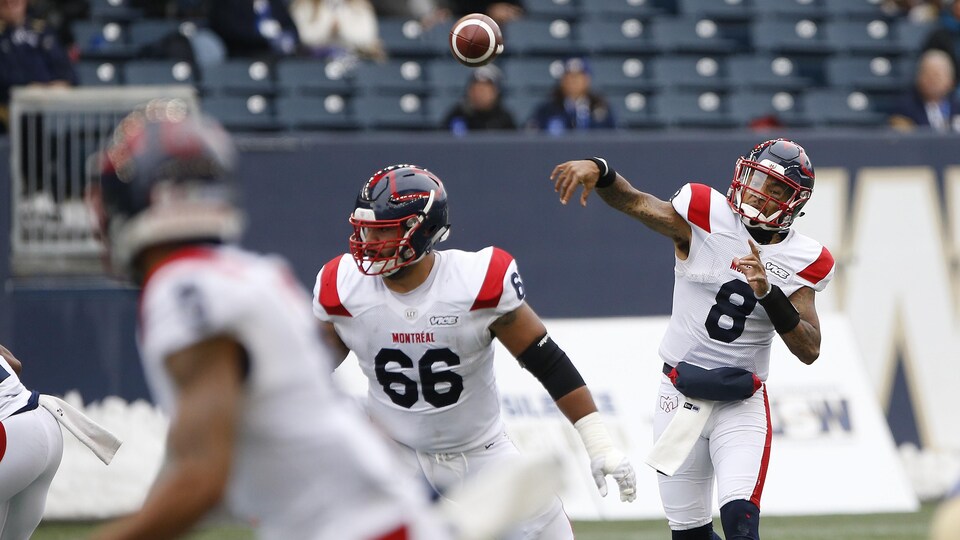 Le quart arrière lance le ballon tout en étant protégé par un joueur de ligne.