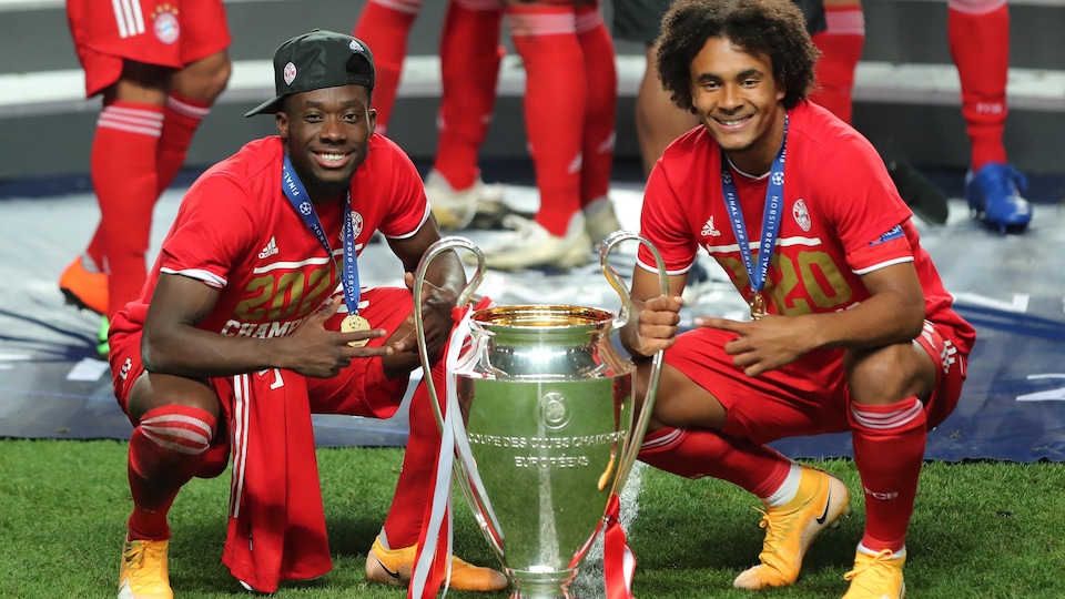 Deux joueurs de soccer du Bayern Munich prennent la pose accroupis avec le trophée remis à l'équipe gagnante de la Ligue des champions de l'UEFA au soccer.