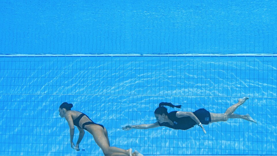 Une femme tente d'agripper une nageuse inconsciente sous l'eau.