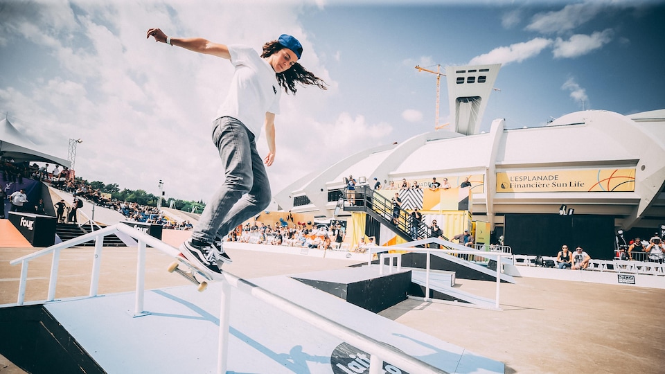 Annie Guglia descent une rampe sur sa planche devant le stade olympique de Montréal.