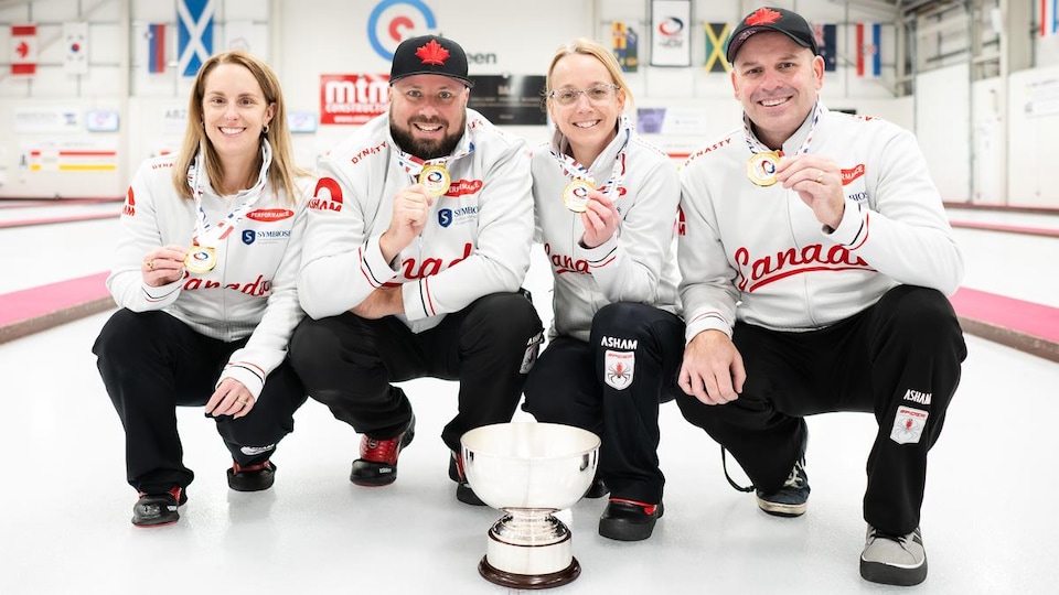 Quatre curleurs canadiens sourient en tenant leur médaille d'or.