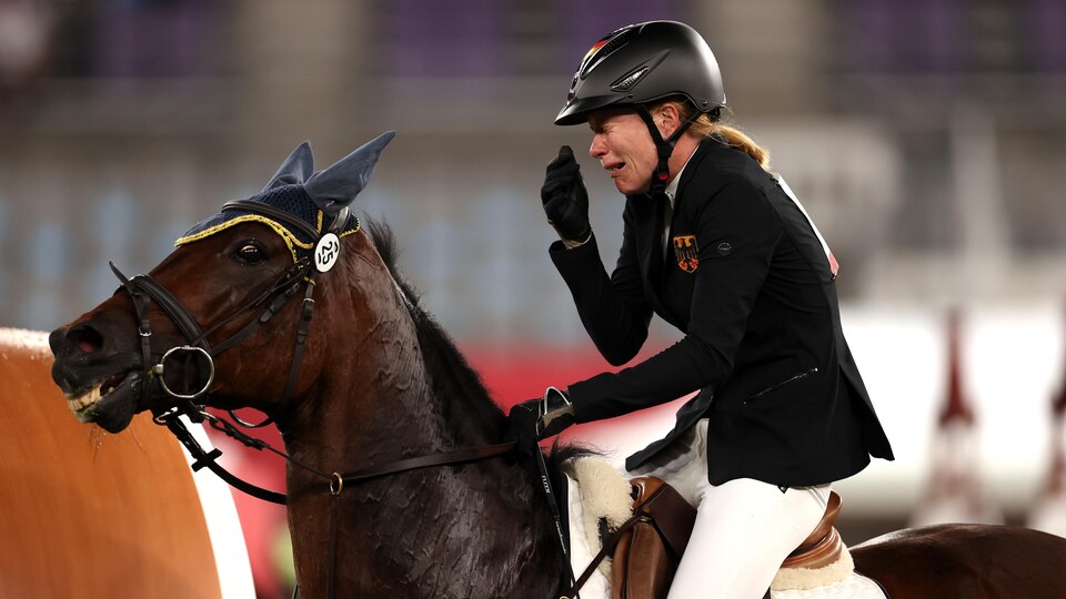 Une femme, qui se trouve sur un cheval, éclate en sanglots.