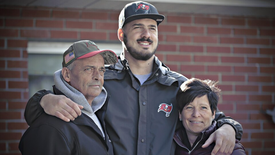 Antony Auclair a un bras autour de chacun de ses deux parents.