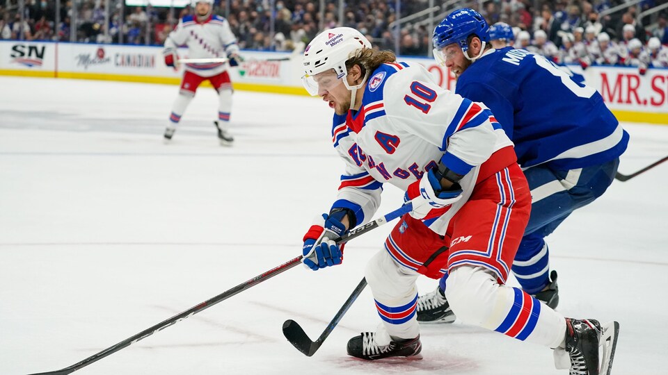 L'attaquant des Rangers protège la rondelle, alors que le défenseur Jake Muzzin tente de la lui enlever.
