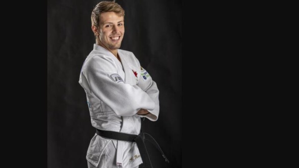 Le judoka Arthur Margelidon a les bras croisés et sourit pour une photo.