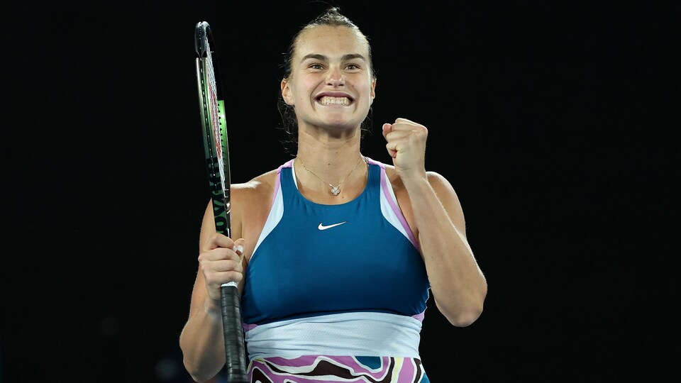 La joueuse de tennis Aryna Sabalenka sourit à pleines dents en serrant le poing gauche.