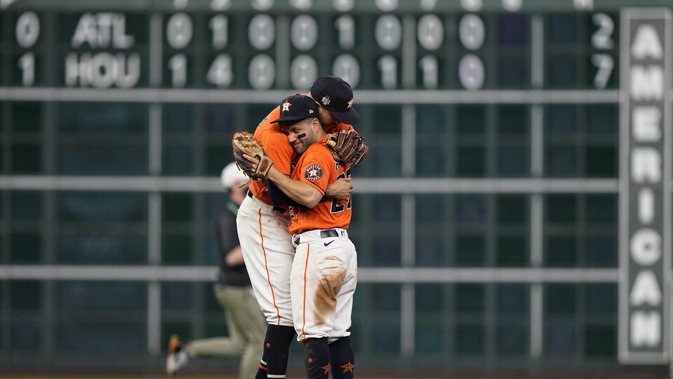 Deux joueurs des Astros, avec leur uniforme orange et blanc, sont dans les bras l'un de l'autre.