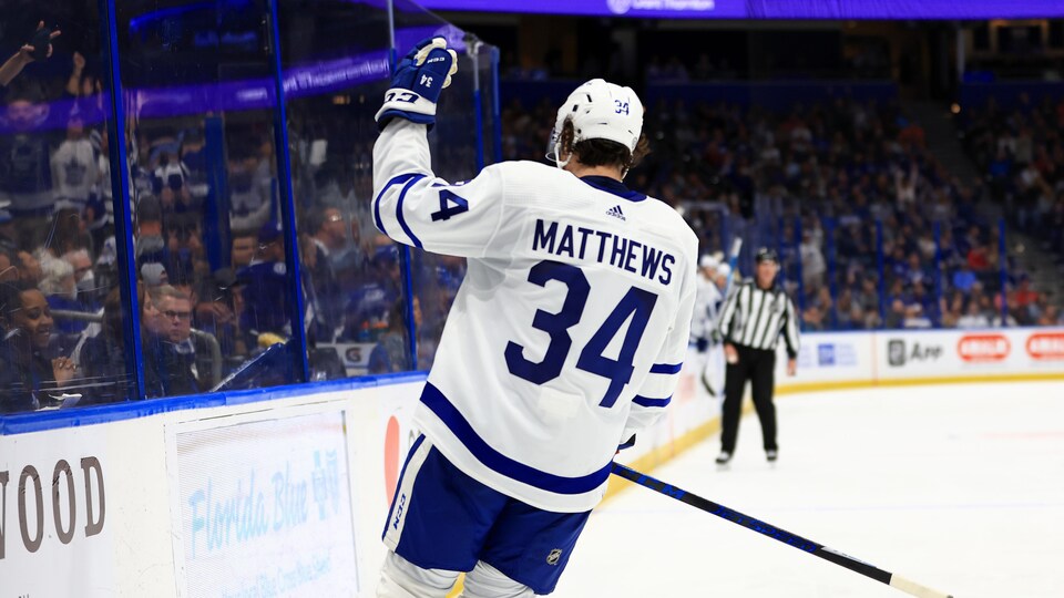 De dos à la caméra, un joueur de hockey salue la foule de la main.