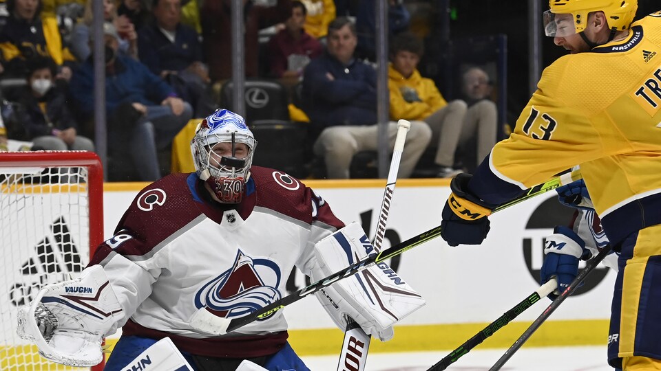 Un joueur de hockey effectue un lancer vers un gardien de but.