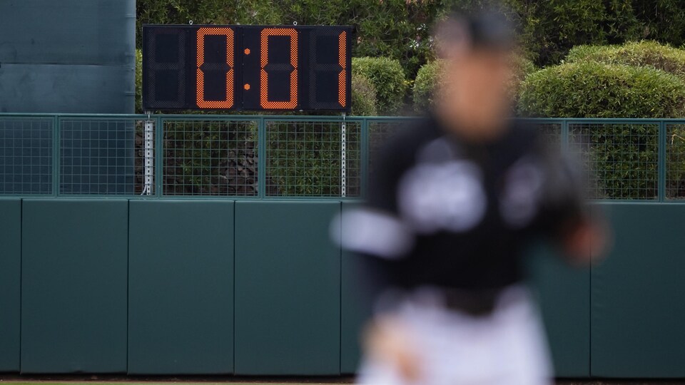 Derrière un joueur sur un terrain de baseball, un cadran géant affiche une seconde restante.