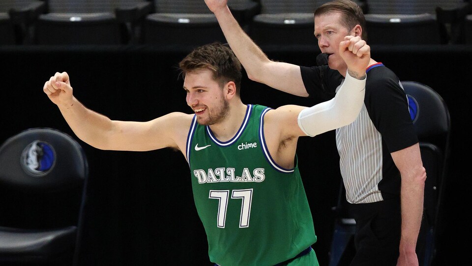 Un joueur de basketball célèbre les bras en l'air.