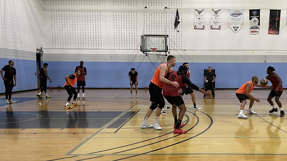 Basketball players compete in a mini game in a gymnasium.