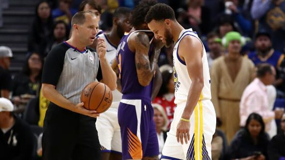 Le basketteur Stephen Curry quitte le court en grimaçant.