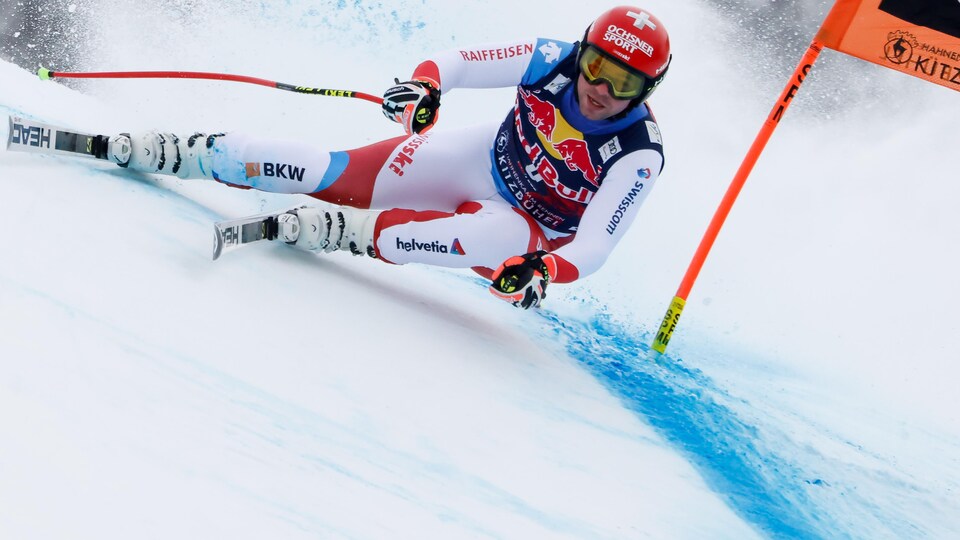 Un skieur négocie un virage à gauche pendant une compétition de vitesse.