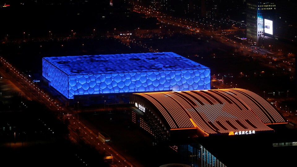 Deux installations sportives massives de Pékin rayonnent dans la nuit grâce à l'éclairage. 