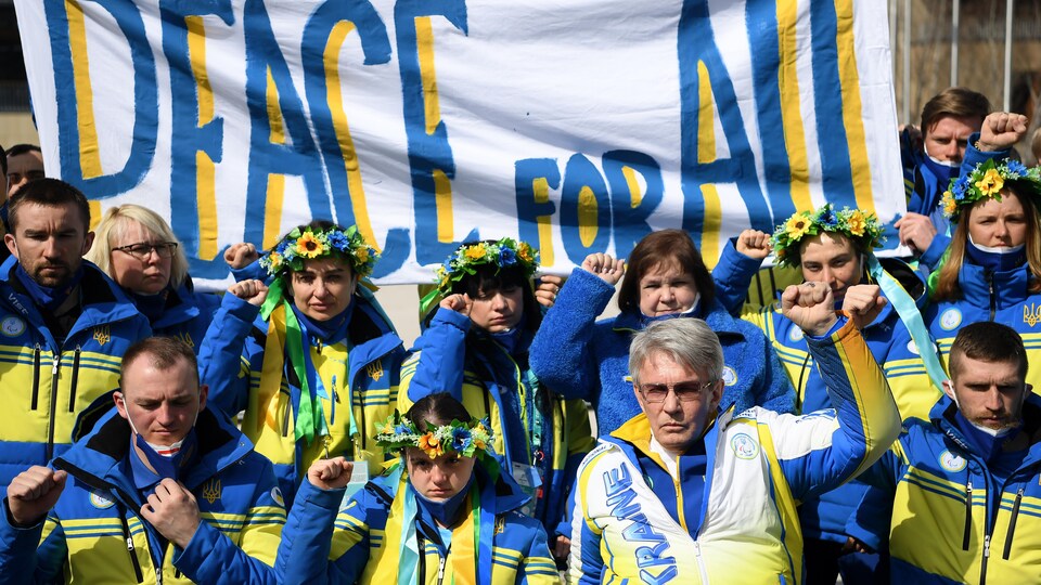 Des Ukrainiens sont réunis devant une bannière où il est écrit «Peace for all».