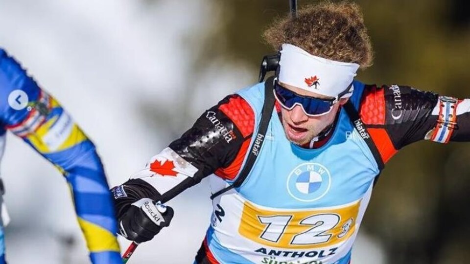 Un biathlonien canadien en plein effort, avec sa carabine dans le dos, lors d'une compétition.