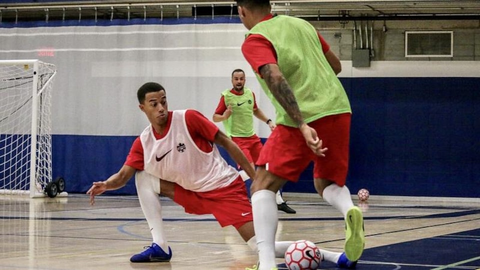 Un joueur de futsal est agenouillé devant un adversaire lors d'un entraînement.