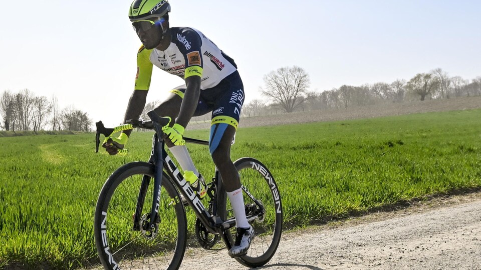 A cyclist is riding on a road on a sunny day.