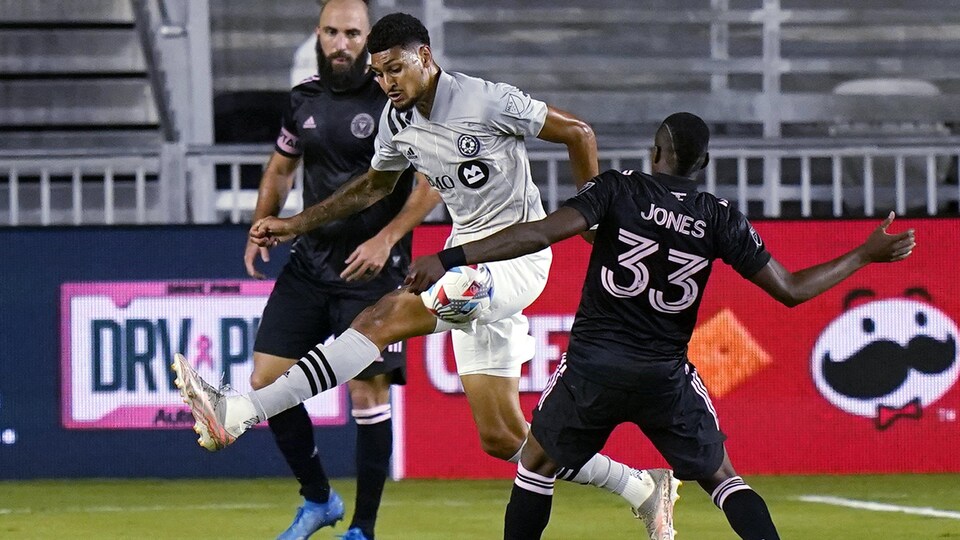 Deux joueurs de soccer se disputent le ballon qui est dans les airs.