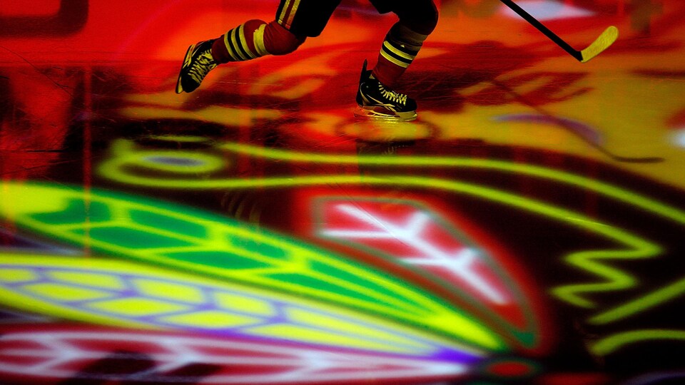 Un joueur des Blackhawks s'échauffe alors que le logo de l'équipe est projeté sur la glace.