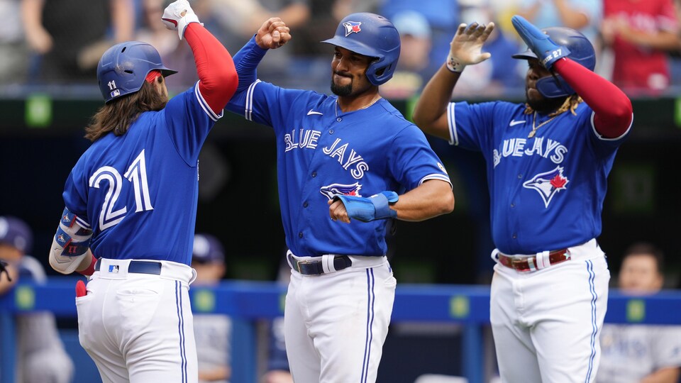 Trois joueurs de baseball se tapent dans les mains.