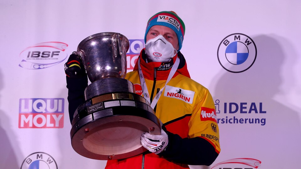 Il tient son trophée dans ses mains.