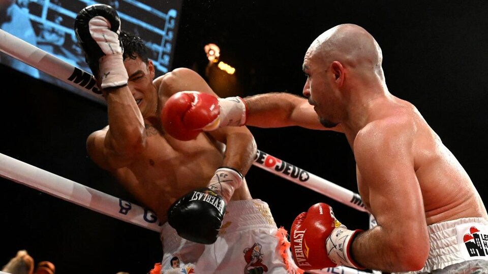 A boxer hits his rival with the right hook.