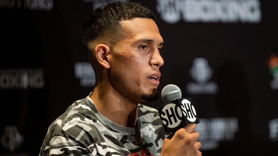 Boxer David Benavidez holds a microphone in one hand.