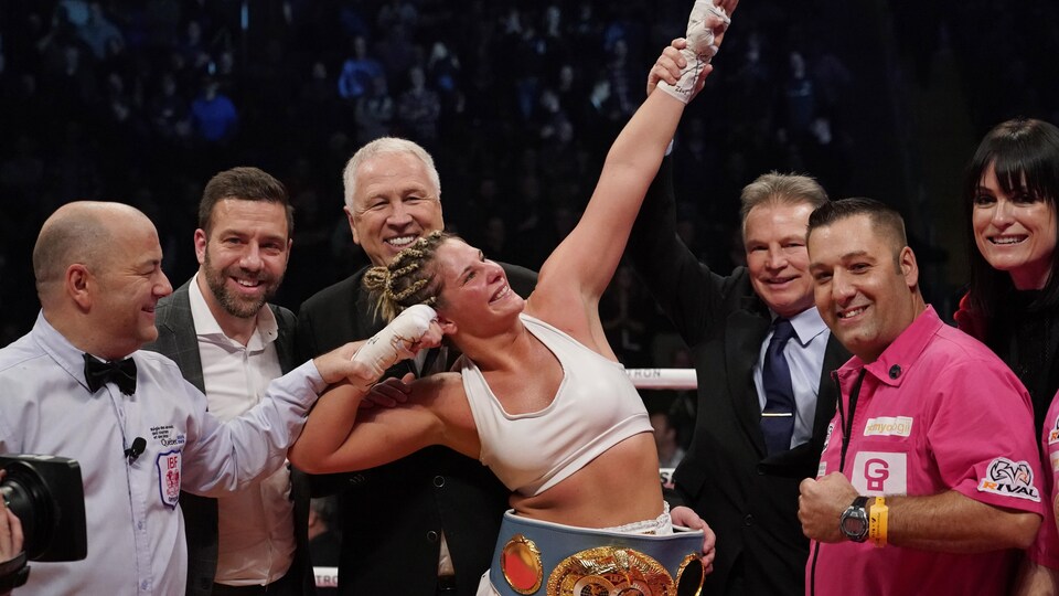 Marie-Ève Dicaire (au centre) célèbre sa victoire contre Chris Namus pour le championnat du monde IBF des super-mi-moyens.
