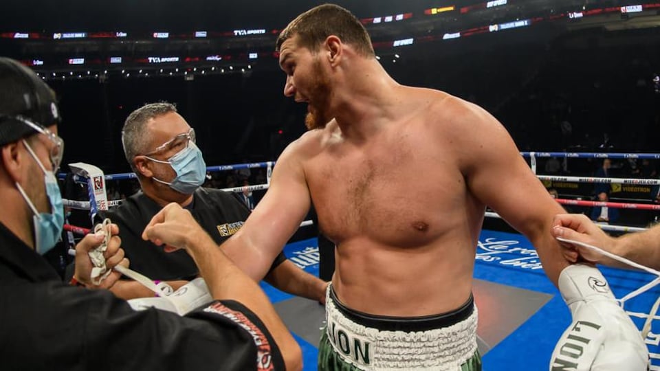 Un entraîneur de boxe félicite son protégé dans le ring après une victoire.