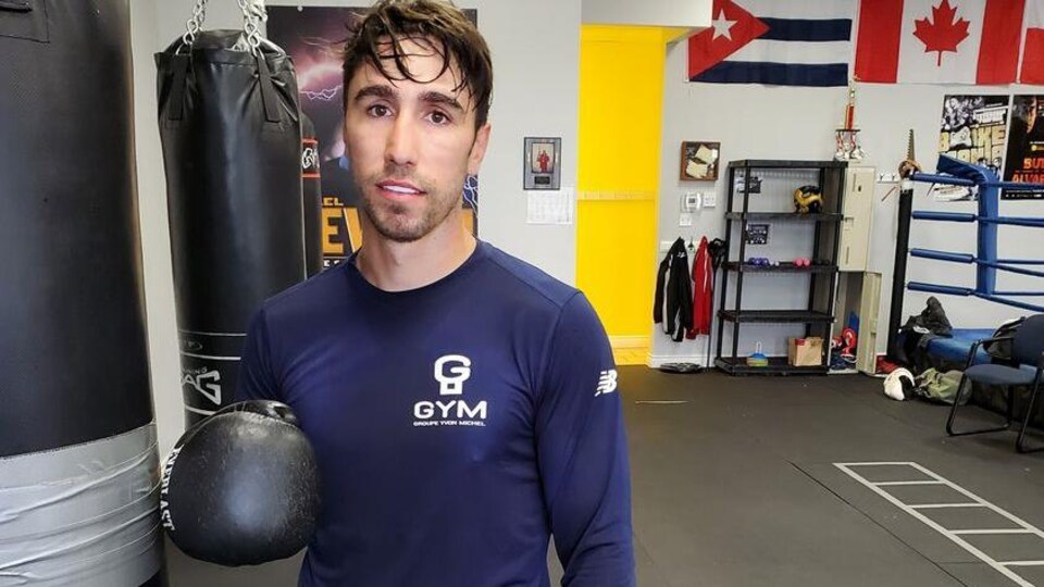 Un boxeur devant un sac de frappe dans un gymnase.
