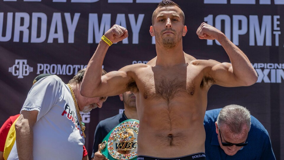 A boxer flaunts his muscles as he steps on the size of the bathroom.