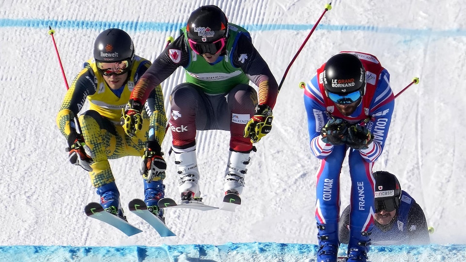Trois skieurs se disputent la tête dans une course de ski cross.