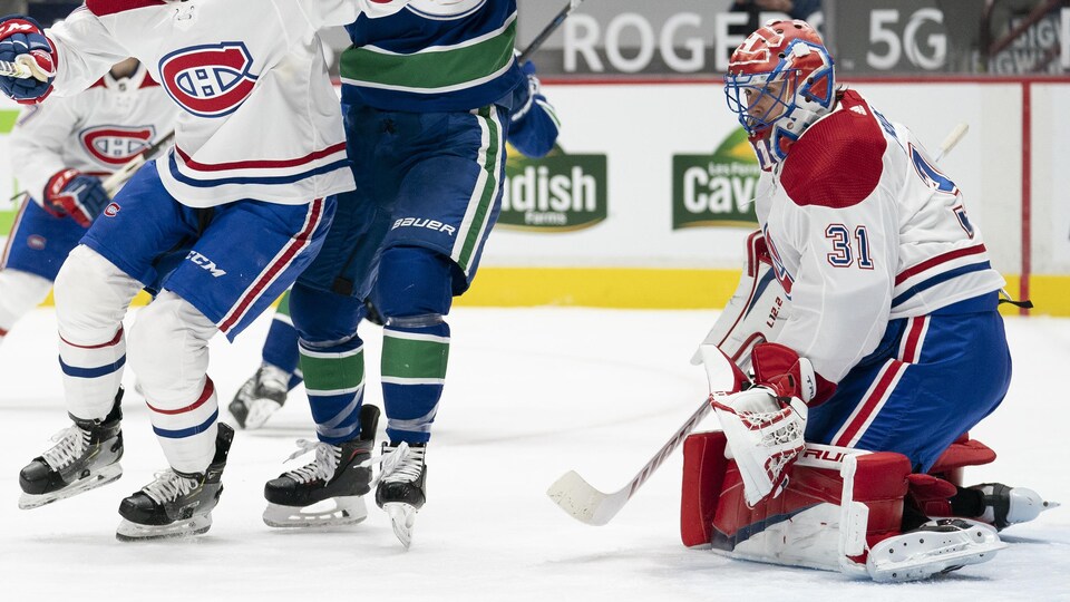 Brett Kulak, Adam Gaudette et Carey Price cherchent la rondelle du regard.