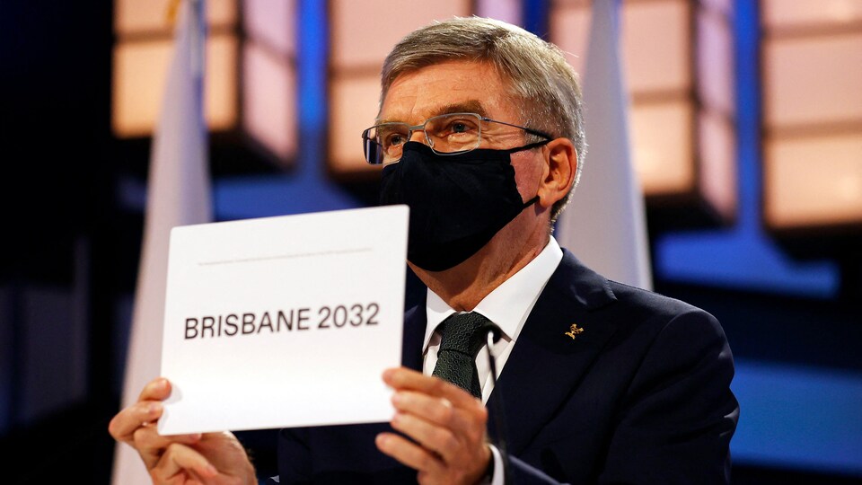 Il présente un carton sur lequel il est écrit Brisbane 2032.