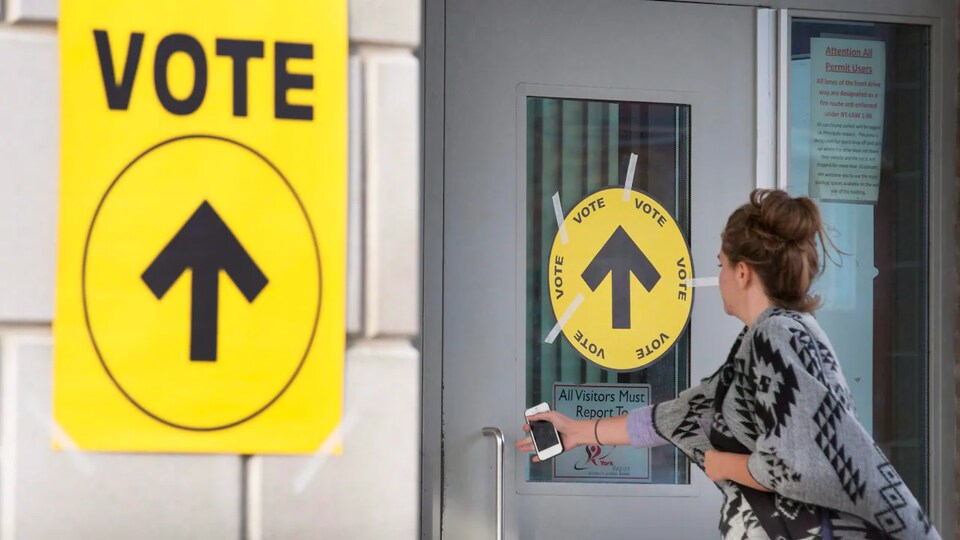 Une femme ouvre la porte d'un bureau de vote.