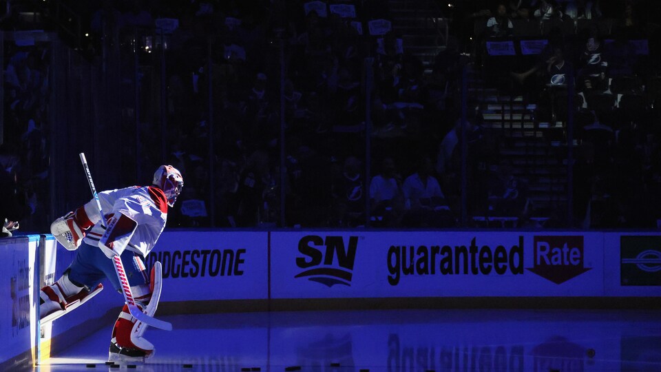 Un gardien but de hockey saute sur la glace, dans la pénombre, le projecteur sur lui.