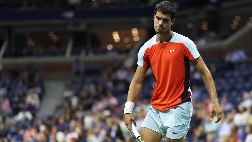 Un joueur de tennis fait la grimace après avoir raté un coup.