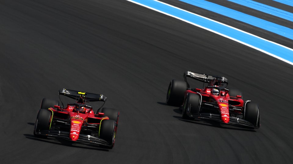 Deux monoplaces de l'équipe Ferrari négocient un virage à droite sur un circuit.