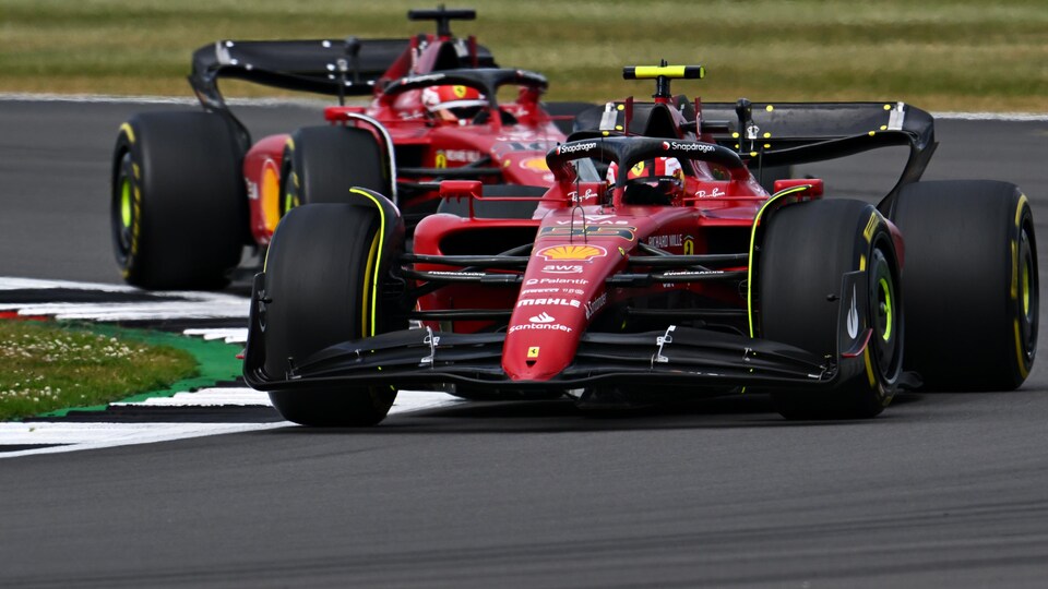 Les deux monoplaces de Ferrari négocient un virage à droite sur un circuit.