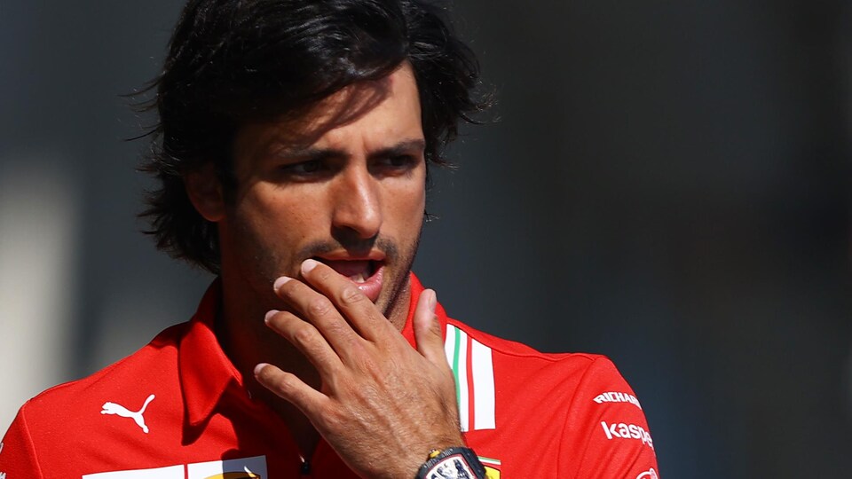 Un pilote de F1 marche, la main gauche sur son visage.
