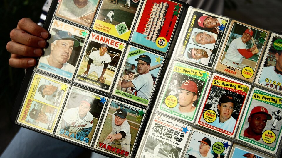 Un homme montre plusieurs cartes de baseball.