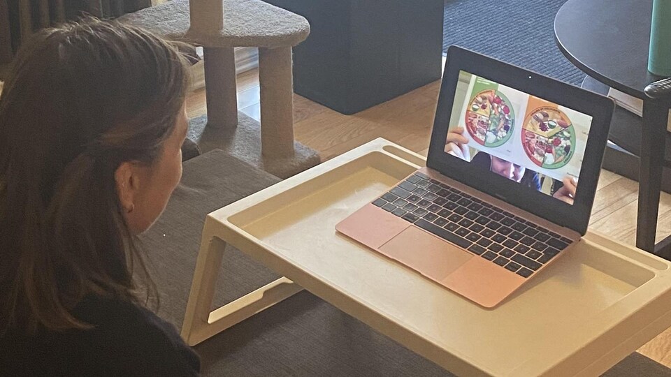 Elle regarde des images de plats sur son ordinateur.