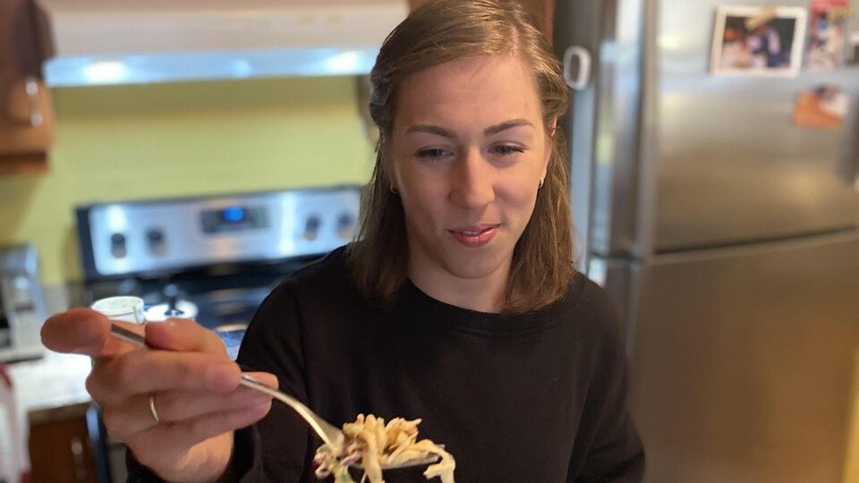 Elle lève une fourchette couverte de pâtes.