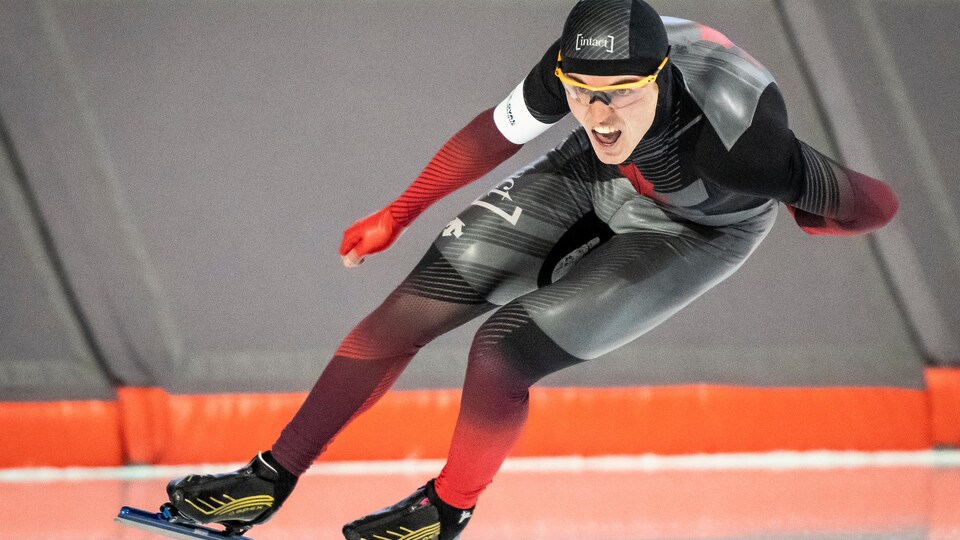 Un patineur de vitesse tire la langue pendant une course.