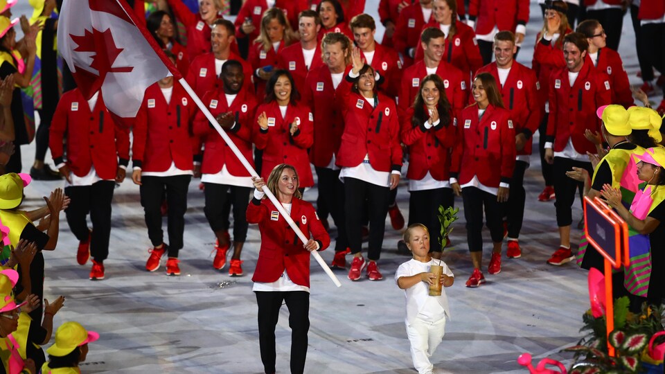 Plan large de Rosie MacLennan, drapeau canadien en main marchant devant la délégation canadienne lors de la cérémonie d'ouverture des Jeux olympiques de Rio.