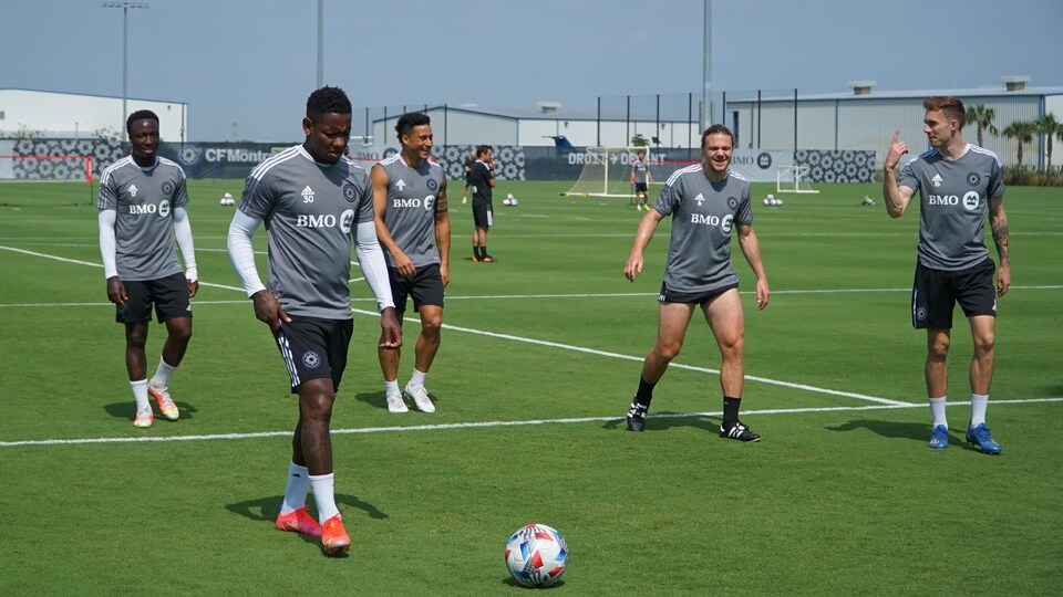 Cinq joueurs de soccer se passent le ballon.