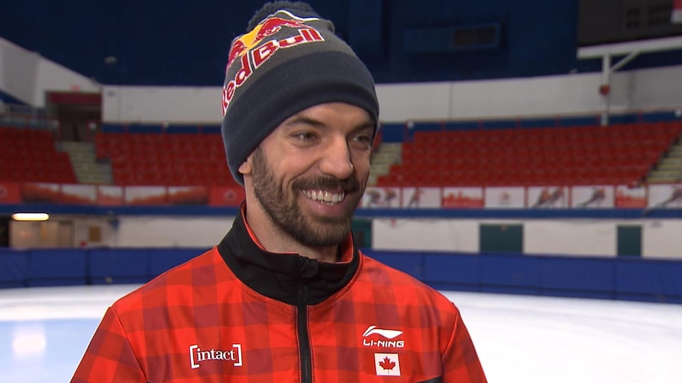 Il sourit sur le bord de la patinoire.