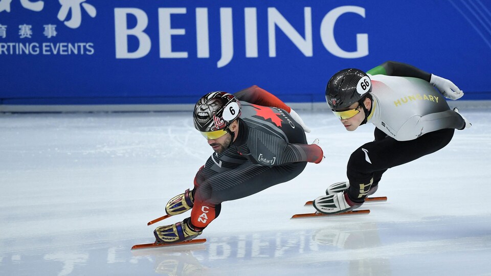 Deux patineurs de vitesse les mains dans le dos dans un virage